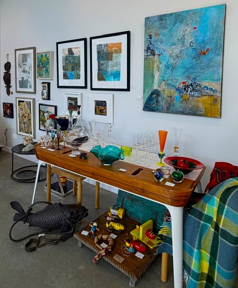 A gallery table displaying glassware, ceramics, and colourful artworks at White House Collectables